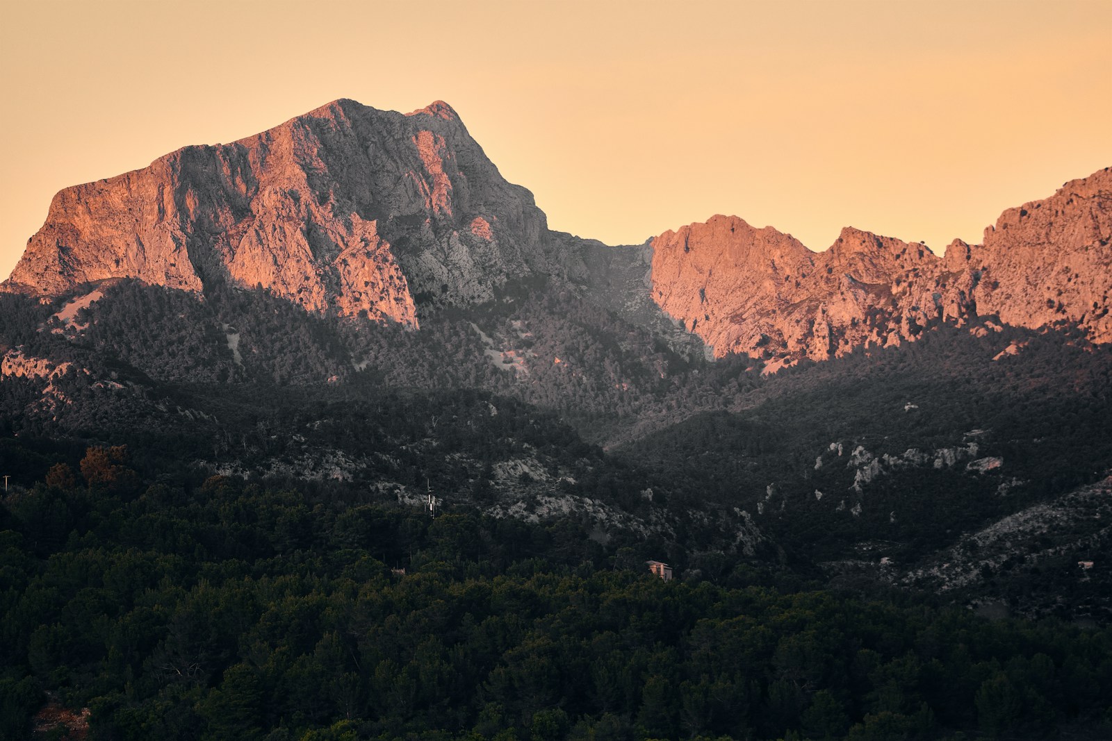 Mountains are bathed in golden sunlight at sunset.